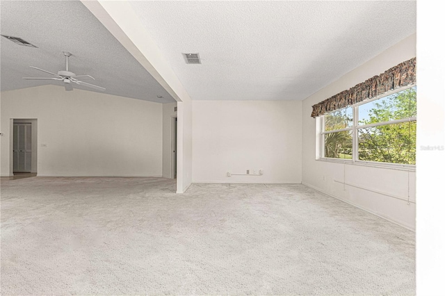 carpeted spare room with a textured ceiling, ceiling fan, and vaulted ceiling