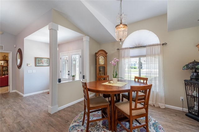 dining space featuring decorative columns, light wood-type flooring, french doors, an inviting chandelier, and vaulted ceiling