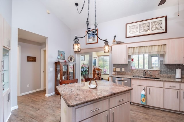 kitchen with a kitchen island, sink, backsplash, light wood-type flooring, and decorative light fixtures