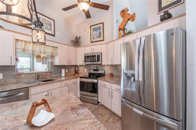 kitchen featuring appliances with stainless steel finishes, tasteful backsplash, light hardwood / wood-style floors, and sink