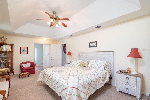 carpeted bedroom with ceiling fan and a raised ceiling