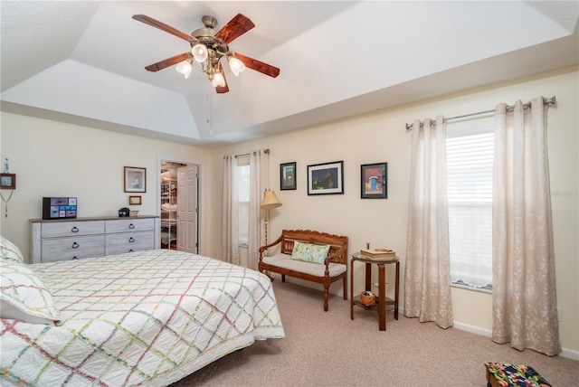 bedroom featuring light colored carpet, a spacious closet, ceiling fan, a closet, and a raised ceiling