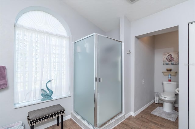 bathroom with a shower with door, toilet, plenty of natural light, and hardwood / wood-style floors