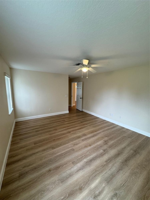 empty room with a textured ceiling, ceiling fan, and hardwood / wood-style floors