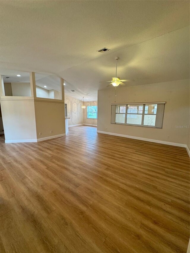 empty room featuring lofted ceiling with beams, ceiling fan, and hardwood / wood-style flooring