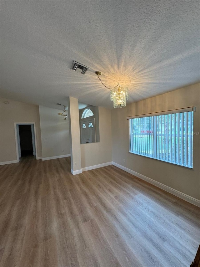 unfurnished living room featuring a textured ceiling, hardwood / wood-style floors, and a chandelier