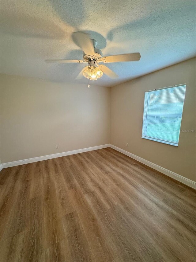 empty room with a textured ceiling, ceiling fan, and hardwood / wood-style floors