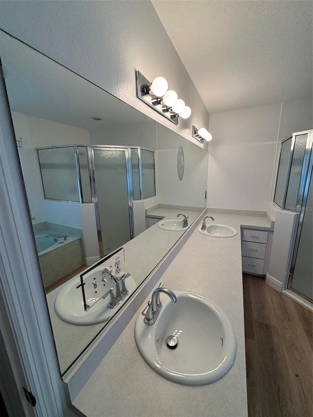 bathroom with separate shower and tub, dual vanity, wood-type flooring, and a textured ceiling