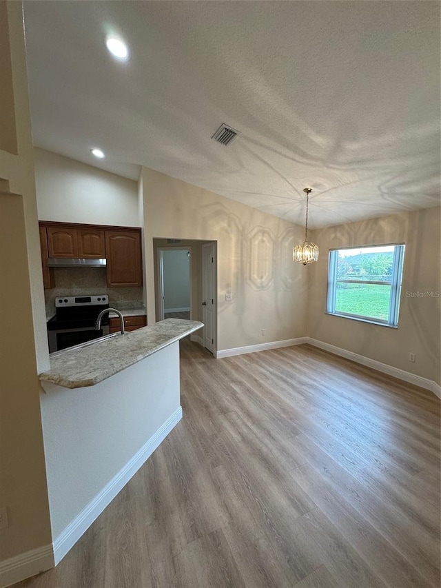 kitchen featuring stainless steel range with electric cooktop, vaulted ceiling, light hardwood / wood-style floors, and decorative light fixtures