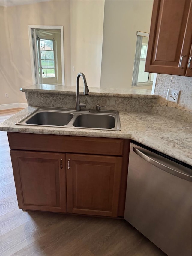 kitchen with sink, stainless steel dishwasher, kitchen peninsula, and hardwood / wood-style floors