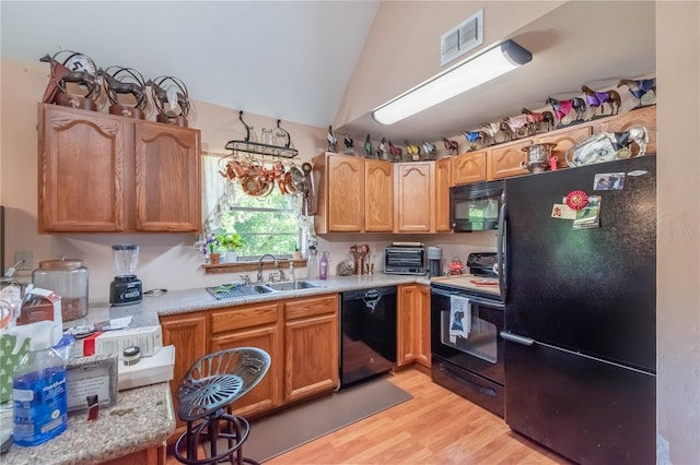 kitchen with sink, black appliances, lofted ceiling, and light wood-type flooring