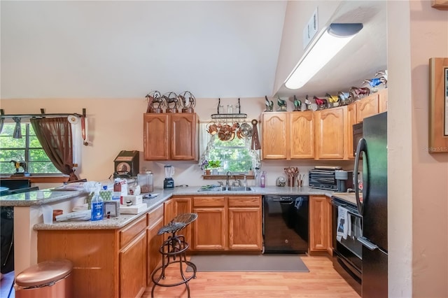 kitchen with sink, light stone counters, kitchen peninsula, black appliances, and light wood-type flooring