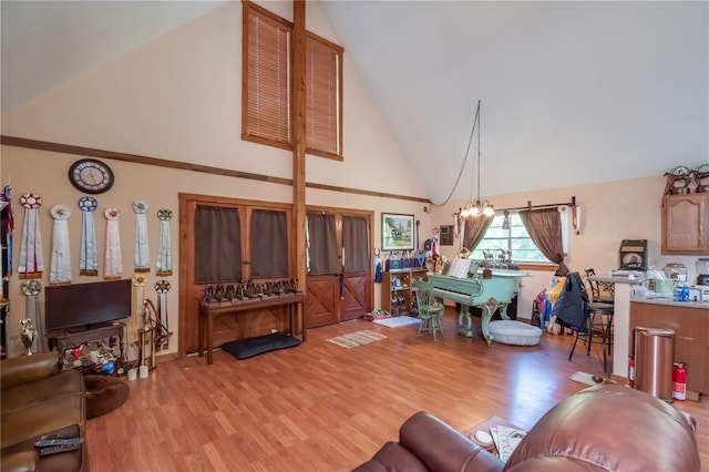 living room featuring high vaulted ceiling, light hardwood / wood-style floors, and a notable chandelier