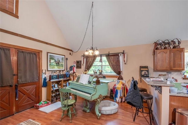 miscellaneous room with a chandelier, light wood-type flooring, and high vaulted ceiling