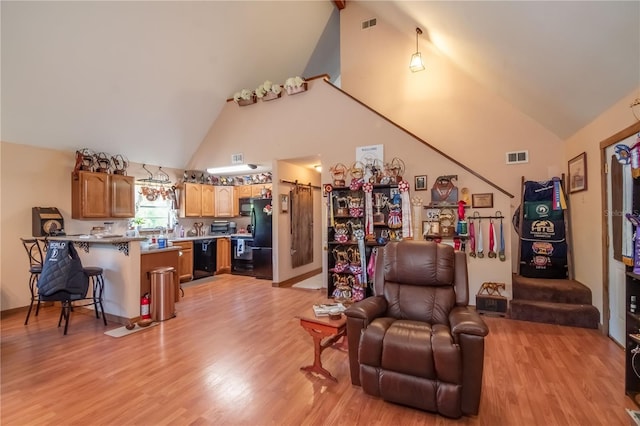 living room featuring light wood-type flooring and high vaulted ceiling