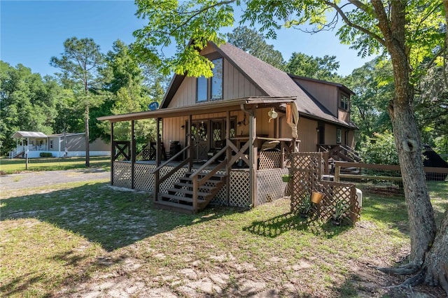 rear view of house with covered porch and a yard