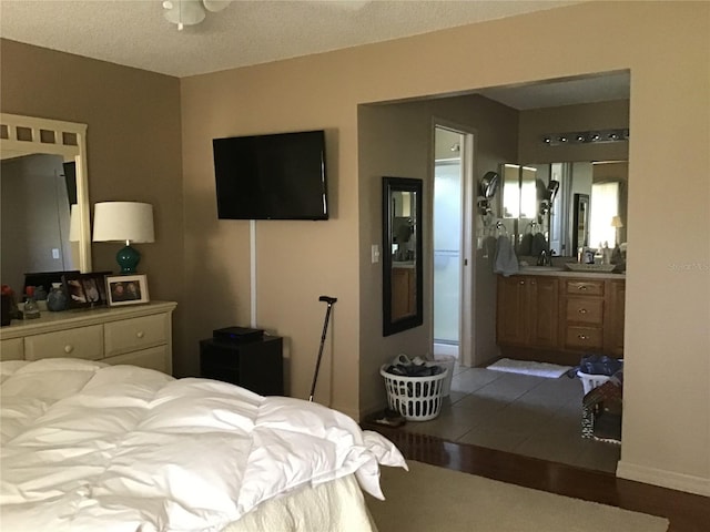 tiled bedroom with a textured ceiling, sink, and connected bathroom