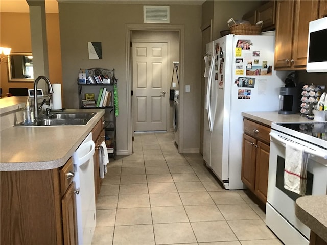 kitchen with white appliances, washer / dryer, sink, and light tile floors