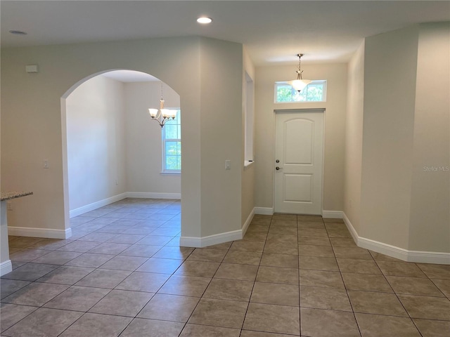 tiled foyer entrance featuring plenty of natural light and a chandelier