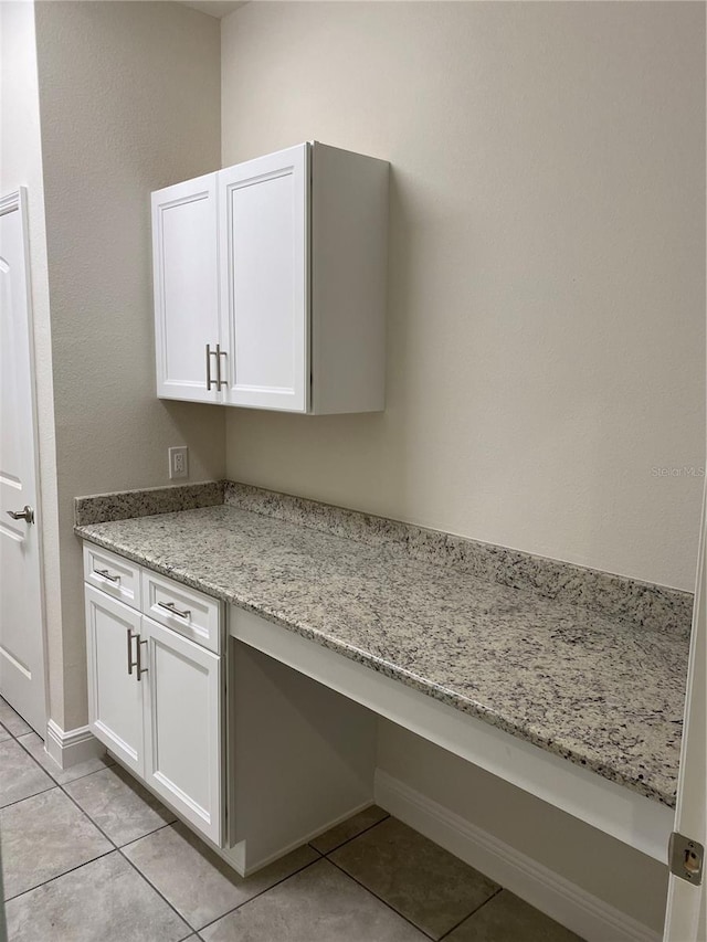 interior space with white cabinets, light tile floors, and light stone countertops