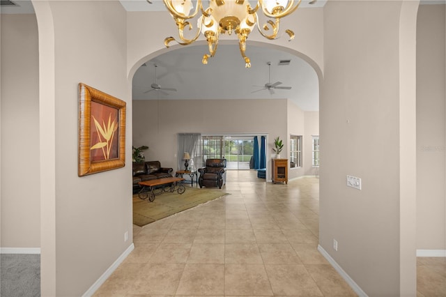 corridor with a high ceiling, light tile patterned floors, and an inviting chandelier