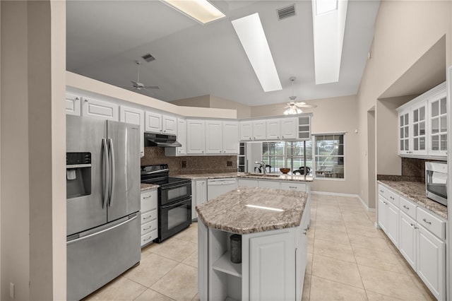 kitchen with white cabinets, a center island, ceiling fan, appliances with stainless steel finishes, and vaulted ceiling with skylight