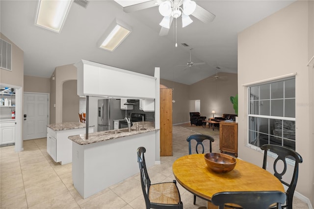 tiled dining area with high vaulted ceiling, sink, and ceiling fan