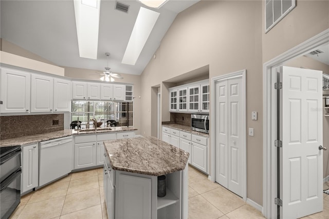 kitchen with white cabinetry, ceiling fan, lofted ceiling with skylight, dishwasher, and a kitchen island