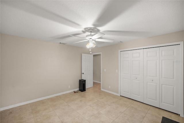 unfurnished bedroom with light tile patterned flooring, a closet, and ceiling fan