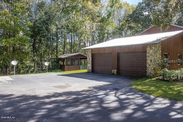 view of property exterior with a garage, an outdoor structure, and a sunroom