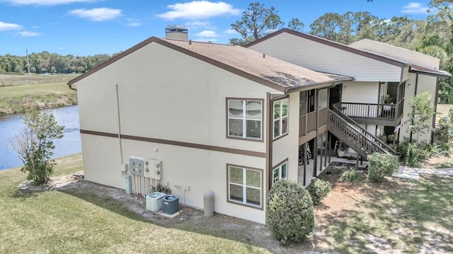 rear view of property featuring a yard, a water view, and central air condition unit