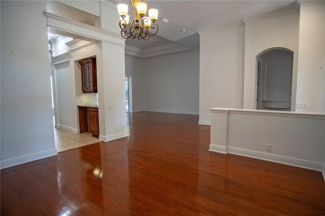 unfurnished room with an inviting chandelier, hardwood / wood-style flooring, and ornamental molding