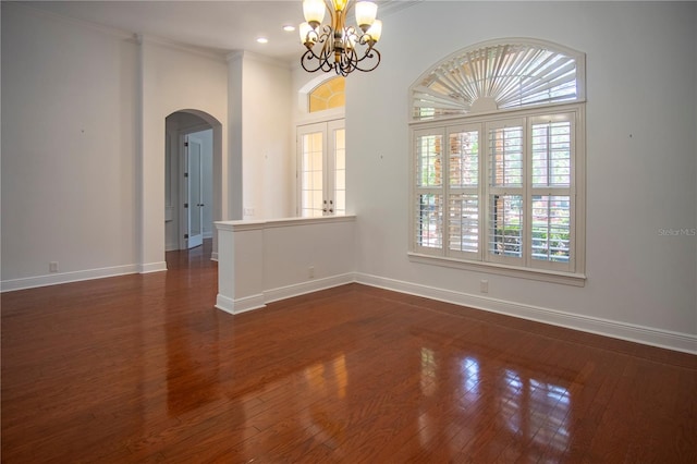 spare room featuring dark hardwood / wood-style flooring, a notable chandelier, and ornamental molding