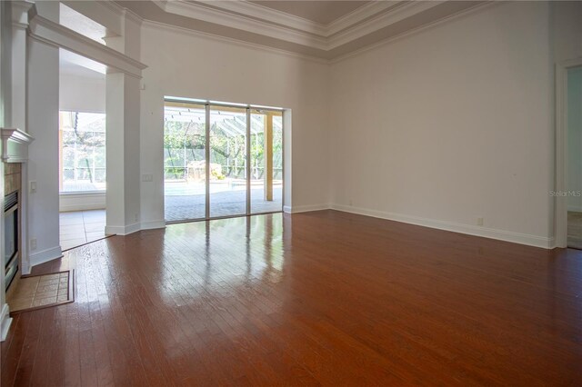 empty room featuring ornamental molding, a tiled fireplace, and dark hardwood / wood-style floors