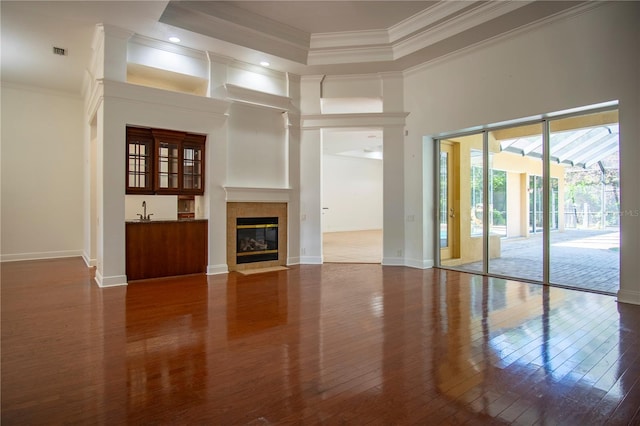 unfurnished living room with a raised ceiling, dark wood-type flooring, a tile fireplace, and a towering ceiling