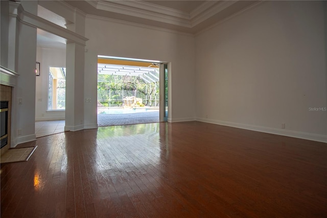 unfurnished living room with ornamental molding, a tray ceiling, dark hardwood / wood-style floors, and a fireplace