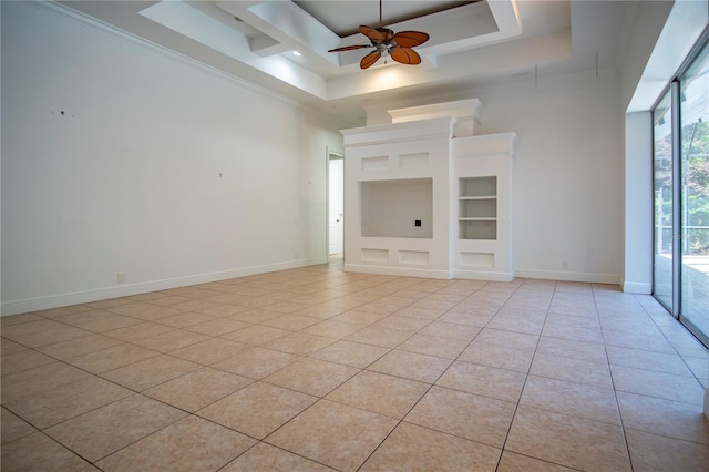 tiled spare room featuring ceiling fan, crown molding, a raised ceiling, and built in shelves