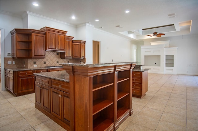 kitchen with a kitchen island, ceiling fan, crown molding, and dark stone countertops