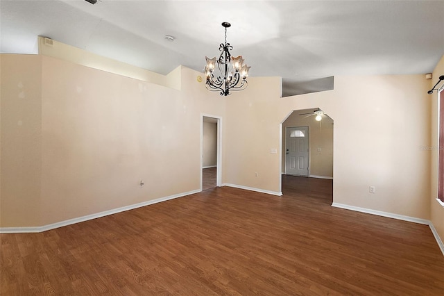 empty room with ceiling fan with notable chandelier and dark wood-type flooring