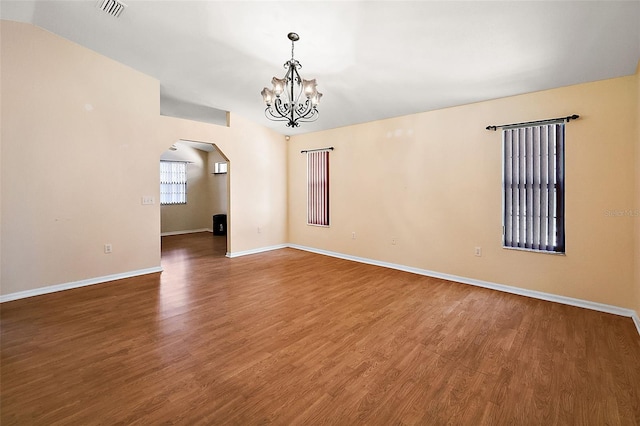 unfurnished room featuring vaulted ceiling, dark hardwood / wood-style flooring, and a notable chandelier