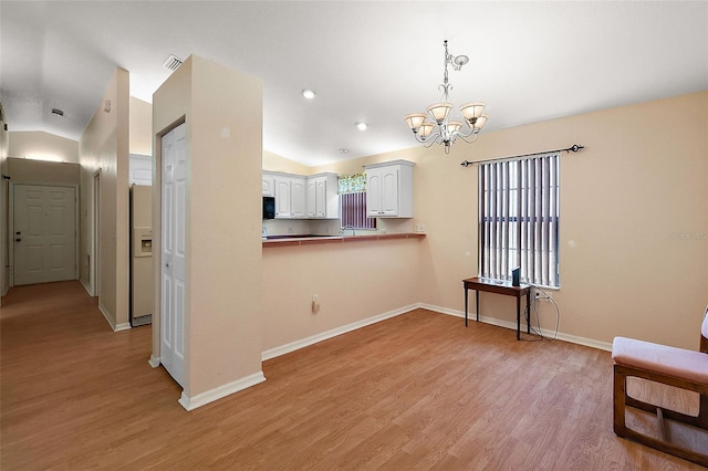 kitchen with a chandelier, light hardwood / wood-style floors, white cabinets, and vaulted ceiling