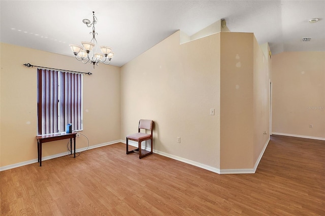 unfurnished room with wood-type flooring, lofted ceiling, and an inviting chandelier