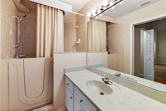 bathroom with tiled shower / bath combo and large vanity