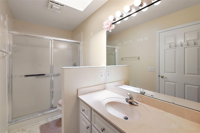 bathroom featuring an enclosed shower, vanity, tile flooring, a skylight, and toilet