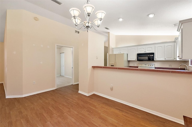 kitchen featuring hardwood / wood-style floors, vaulted ceiling, white fridge with ice dispenser, and range