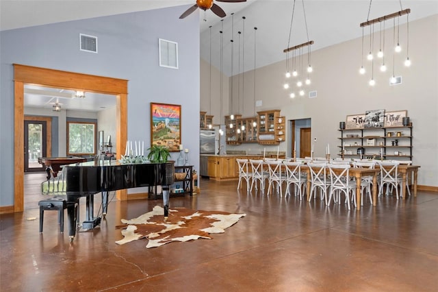 dining space featuring concrete floors, ceiling fan, a towering ceiling, and billiards