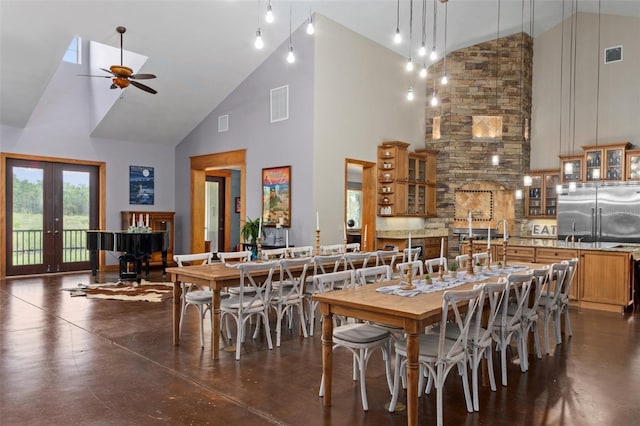 dining room featuring french doors, a skylight, ceiling fan, and high vaulted ceiling