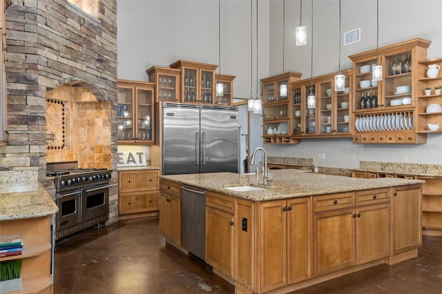 kitchen featuring a center island with sink, a high ceiling, hanging light fixtures, and high end appliances