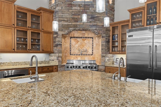 kitchen featuring sink, light stone countertops, built in refrigerator, and range