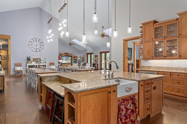 kitchen with pendant lighting, high vaulted ceiling, ceiling fan, and light stone counters